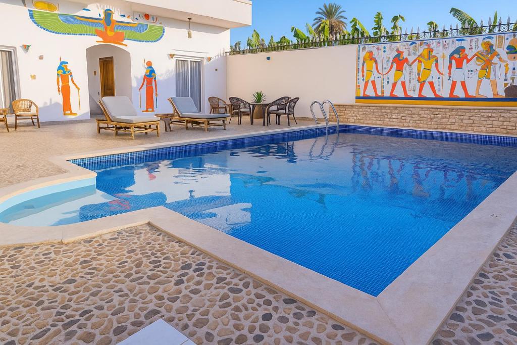 a swimming pool with blue water in front of a building at Villa Desert Rose in Luxor