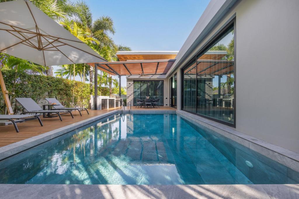 an indoor swimming pool with a patio and a house at VILLA PULAU 3 bedroom Baan Bua Estate in Nai Harn Beach