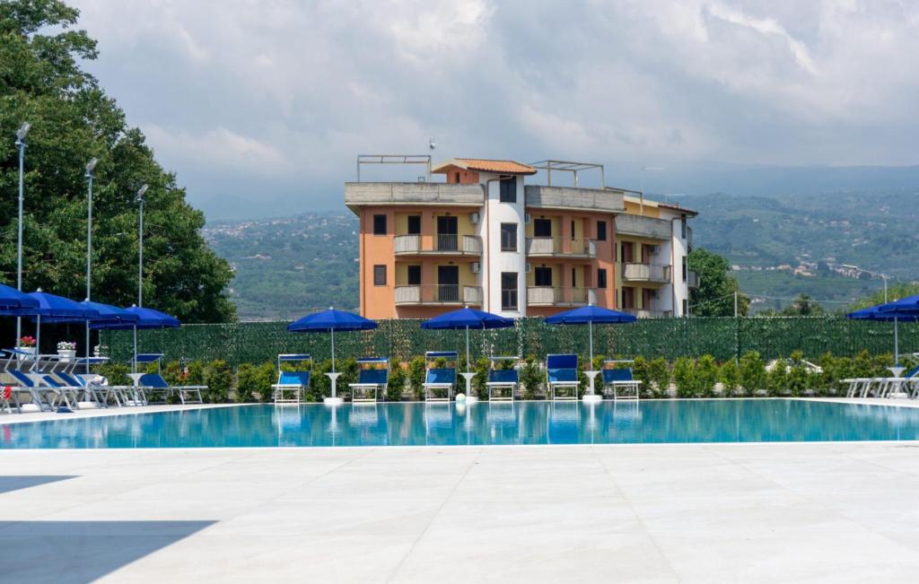 a hotel with a swimming pool with chairs and umbrellas at Teresan Homestay in Mascali