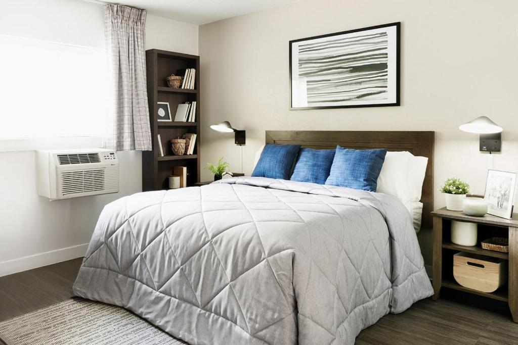 ein Schlafzimmer mit einem großen Bett und blauen Kissen in der Unterkunft InTown Suites Extended Stay Atlanta GA - Snellville in Snellville