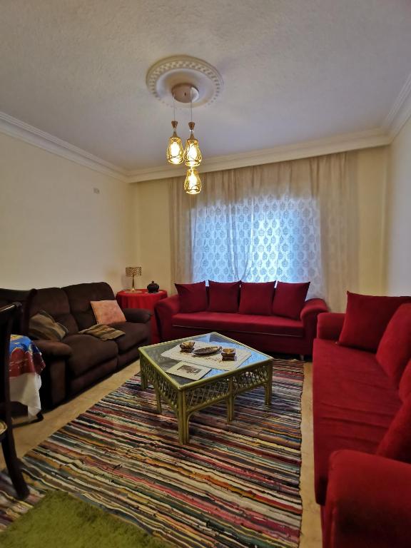 a living room with red couches and a coffee table at Jubeiha Home in Amman