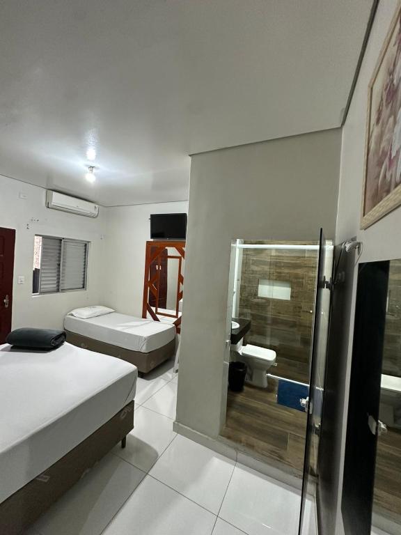 a room with two beds and a shower in it at Hotel Carrão in São Paulo