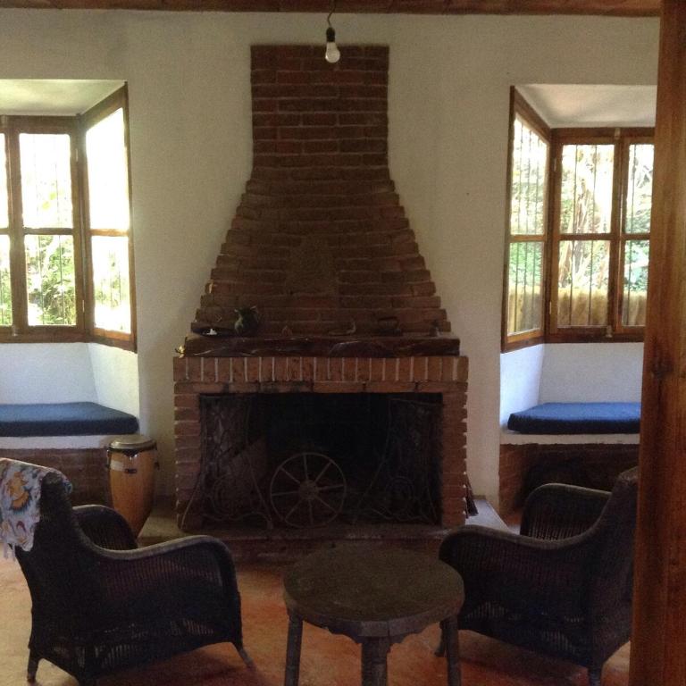 a living room with a brick fireplace with two windows at Casa Cafetal Coatepec in Coatepec