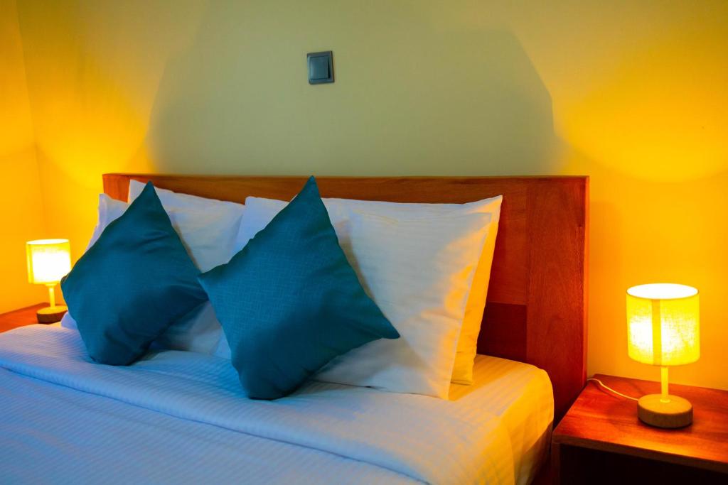 a bedroom with a bed with blue pillows and two lamps at Fort Arch Eco-Lodges in Fort Portal