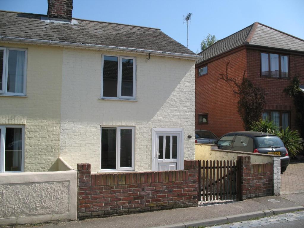 a white house with a brick fence in front of it at Cosy Cottage to Relax or Explore in Mistley