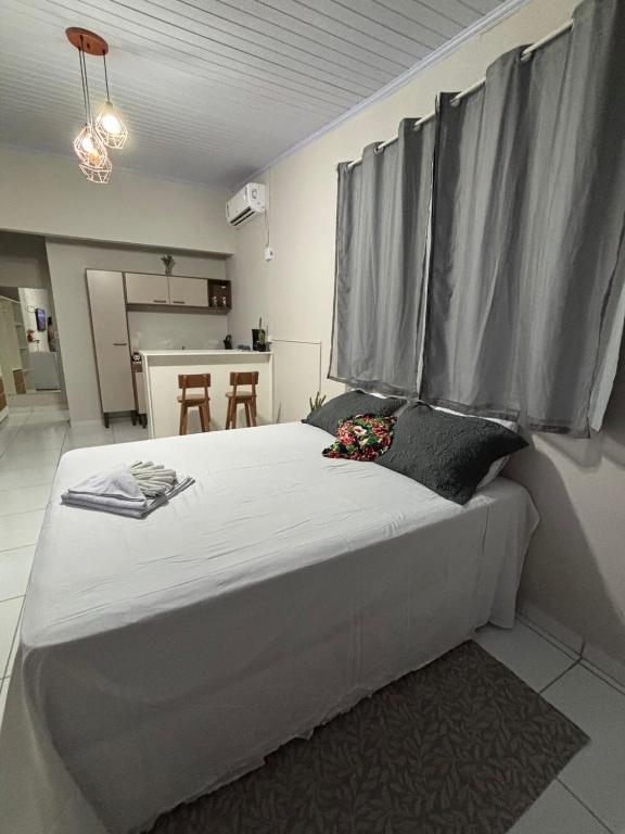 a bedroom with a large white bed with grey curtains at Chalé da Ana in Tutóia