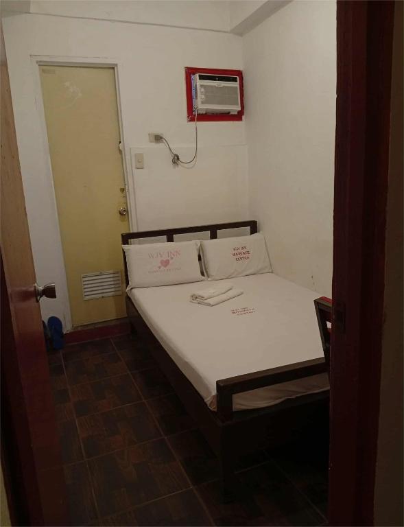 a small bedroom with a bed with white sheets at Wjv Inn Lahug II in Mandaue City