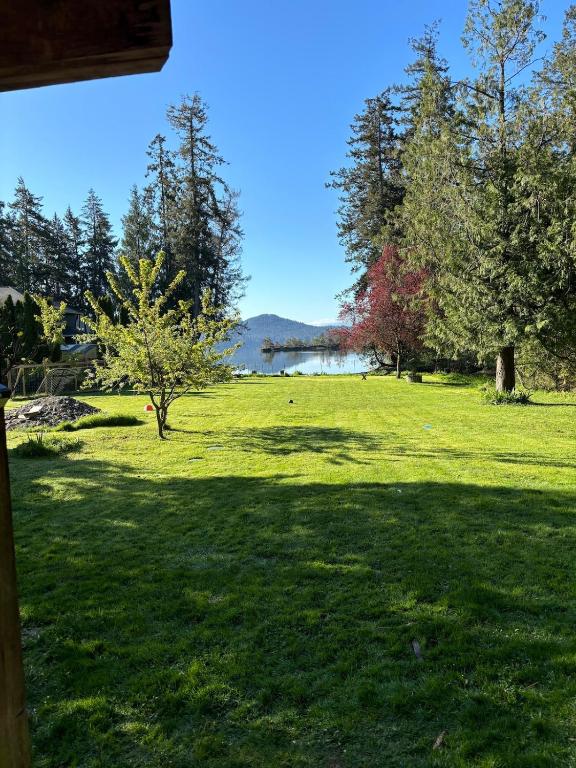 a field of green grass with trees and a lake at Coastal Drift Sooke in Sooke