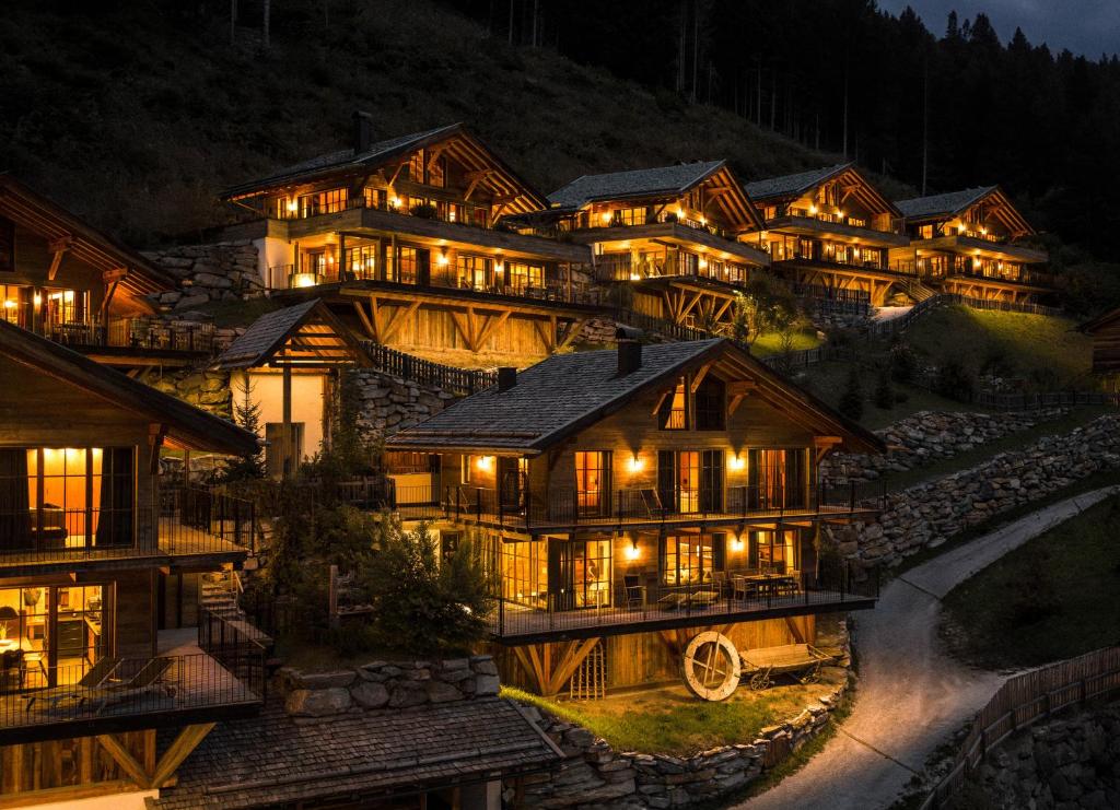 a large wooden building with lights on it at night at Mons Silva Private Luxury Chalets in Racines
