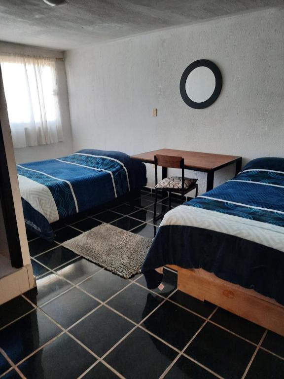 a bedroom with two beds and a table in it at Casa del Parque en Toluca in Toluca