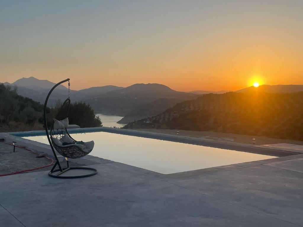 a pool with the sunset in the background at Casa Laguna in Iznájar
