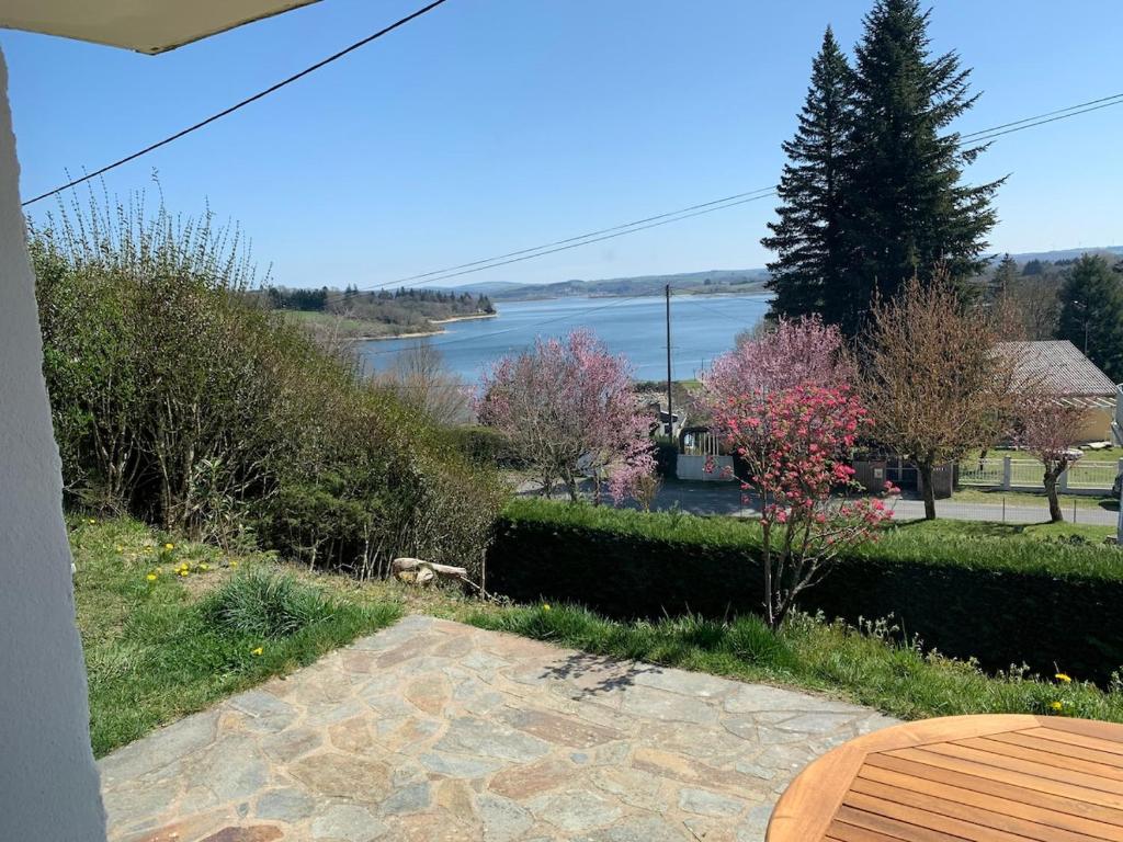 a view of a lake from a yard with a table at Confortable appartement vue lac de Pareloup in Arvieu