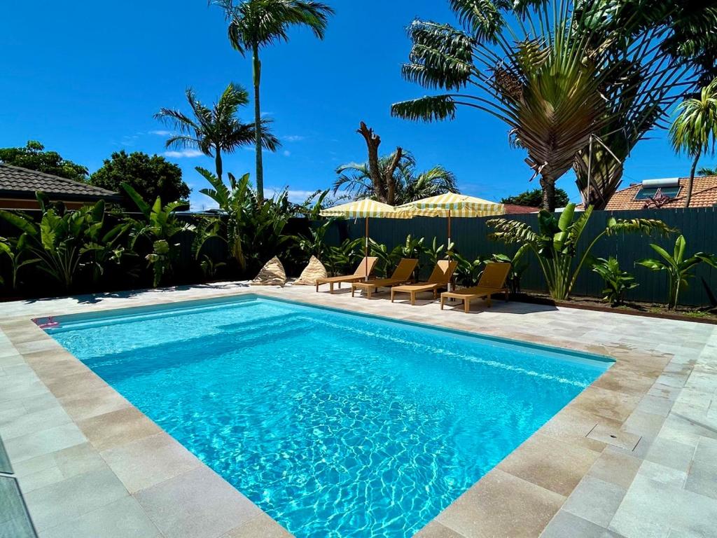 a swimming pool in a yard with chairs and trees at Ballina Oasis in Ballina