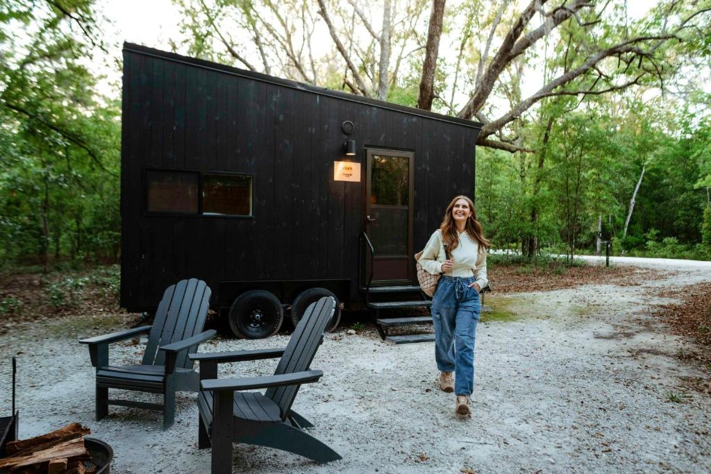 a woman standing in front of a black tiny house at Postcard Cabins St Francois, Outdoor Collection by Marriott Bonvoy in Bloomsdale