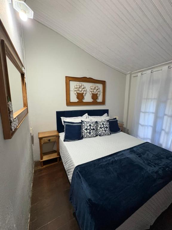 a bedroom with a bed with blue and white pillows at Pousada Dom Luiz in Ouro Preto