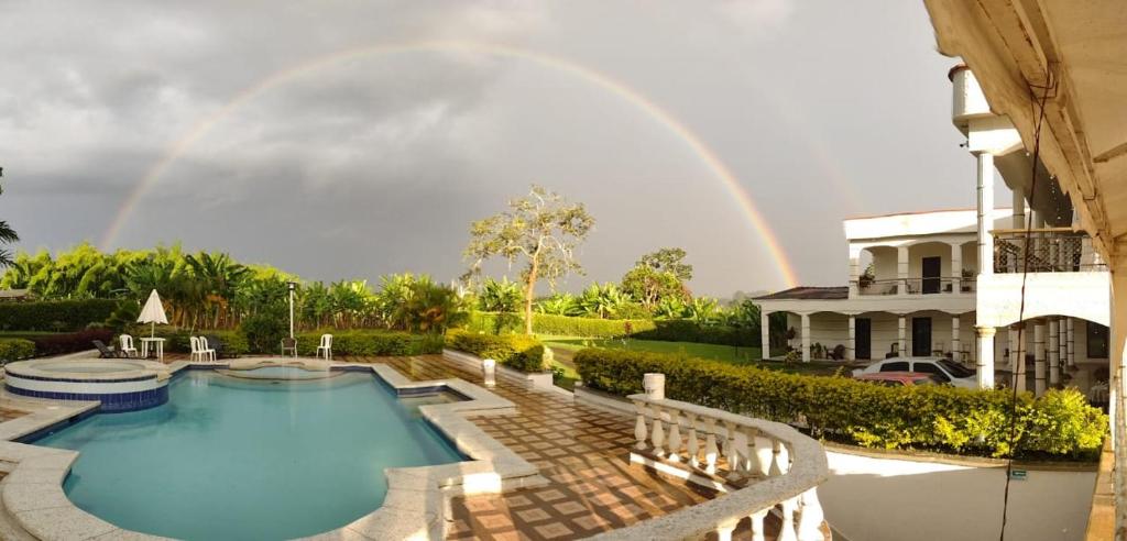 a rainbow over a swimming pool with a house at mansion cafetera in Quimbaya