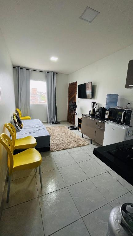a room with a bed and chairs and a kitchen at Vitallino Apartment | Modern with A/C, 10 min from the City Center in Caruaru