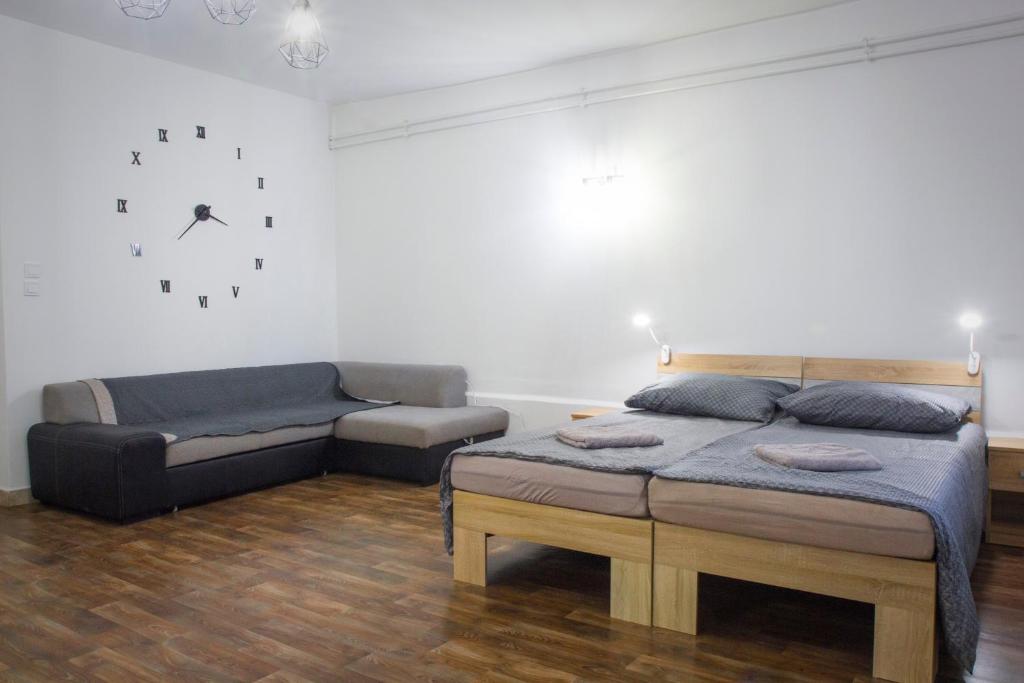 a bedroom with two beds and a couch and a clock at Bázis Vendégház Hajdúnánás in Hajdúnánás