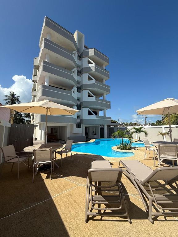 a hotel with chairs and umbrellas next to a pool at Moderno apartamento 1 minuto de la playa in Chichiriviche
