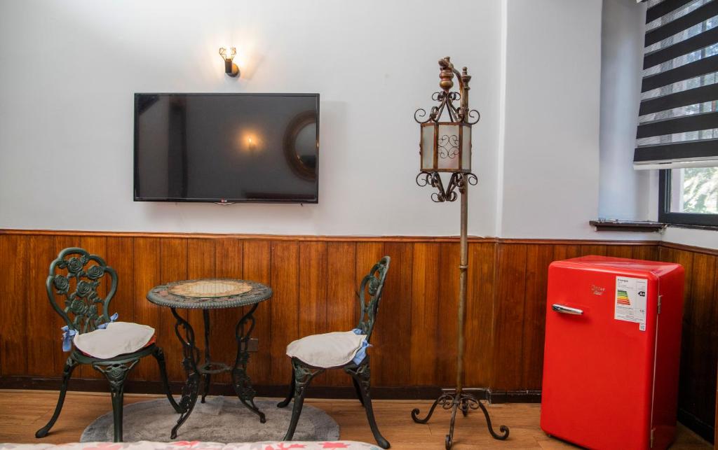a room with a table and two chairs and a red refrigerator at Hotel La Castellana in Santiago