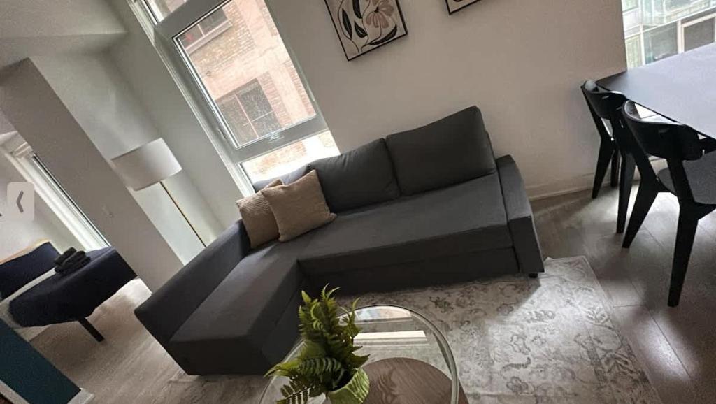 a living room with a black couch and a table at Condo with grey sofa bed in Port Hope