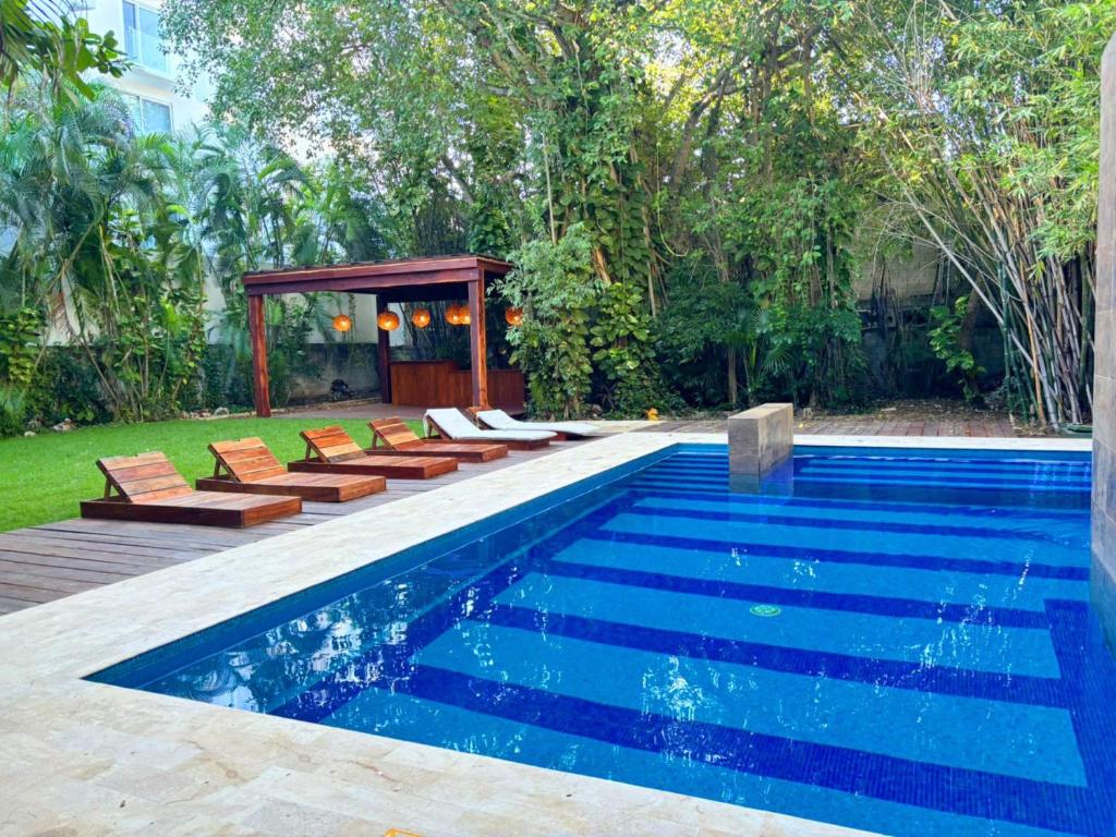 a swimming pool with chairs and a gazebo at Quinta Nina Playa del Carmen - Solo Adultos in Playa del Carmen