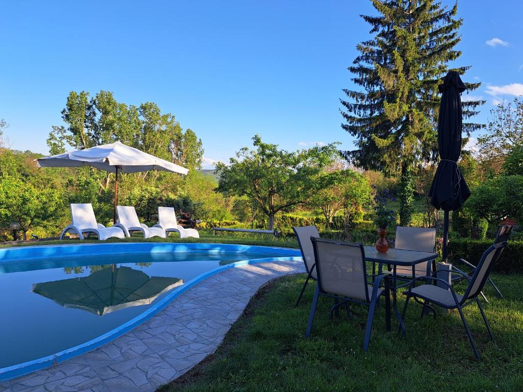 a pool with chairs and a table and an umbrella at Дядо Цоньовата къща самостоятелен имот с басейн in Sevlievo