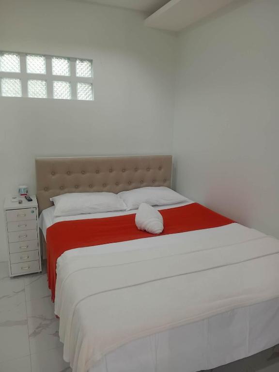 a white bedroom with a large bed with a red blanket at MANEL Guest House - Donsol, Philippines in Donsol