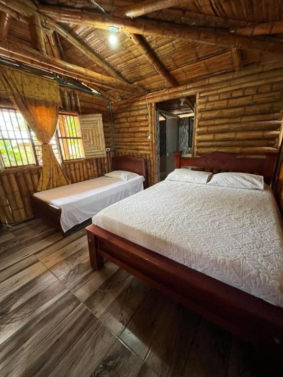 a bedroom with two beds in a log cabin at Cabañas Aires de mi campo in Paicol