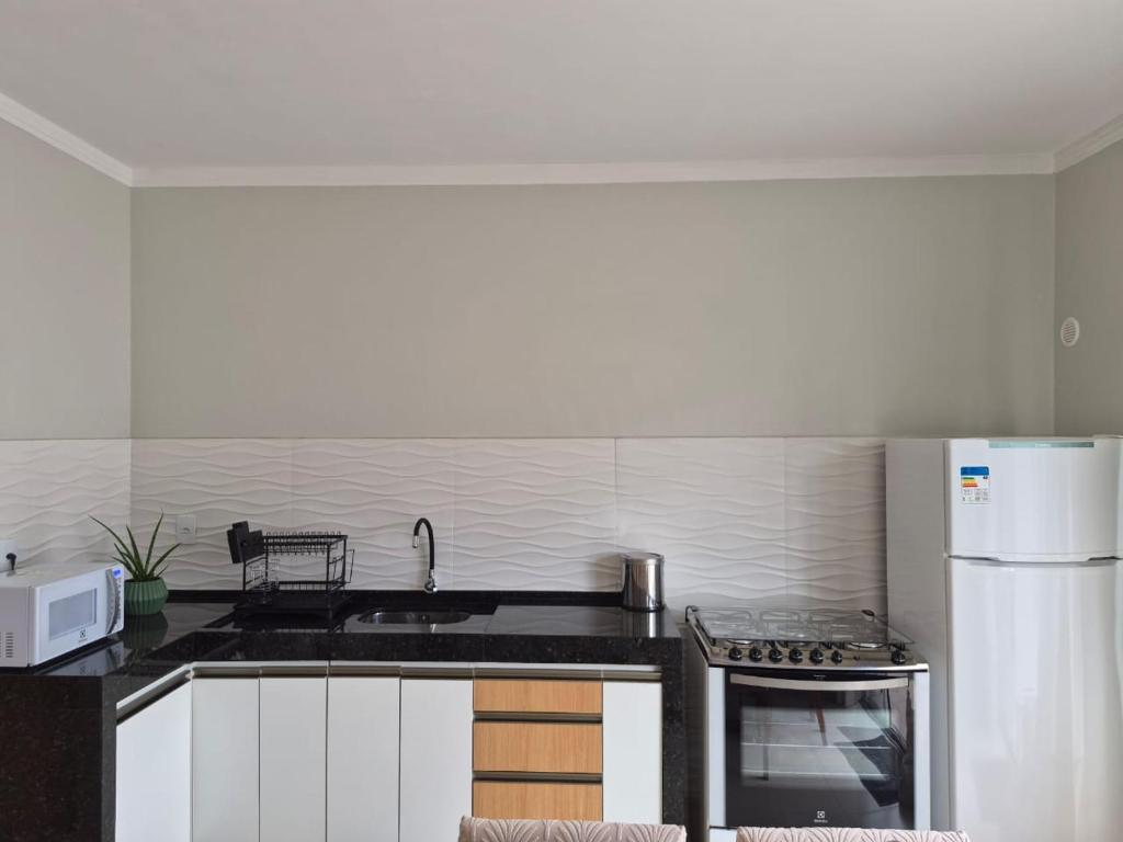 a kitchen with a sink and a refrigerator at Casinha Encantada da MaLu in Itapema
