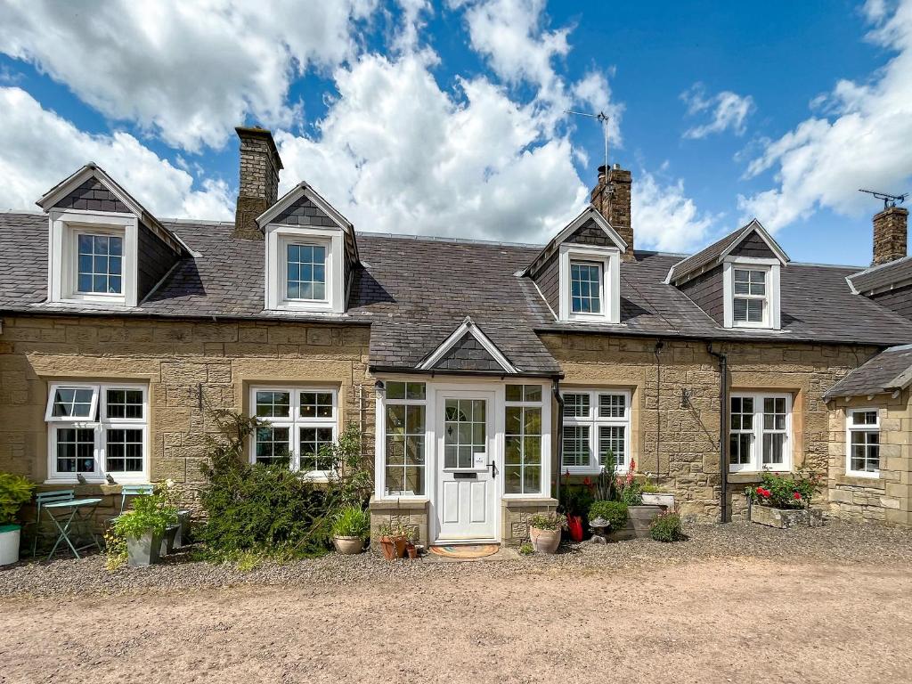a large brick house with a white door at Swinton Mill Farm Cottage in Duns