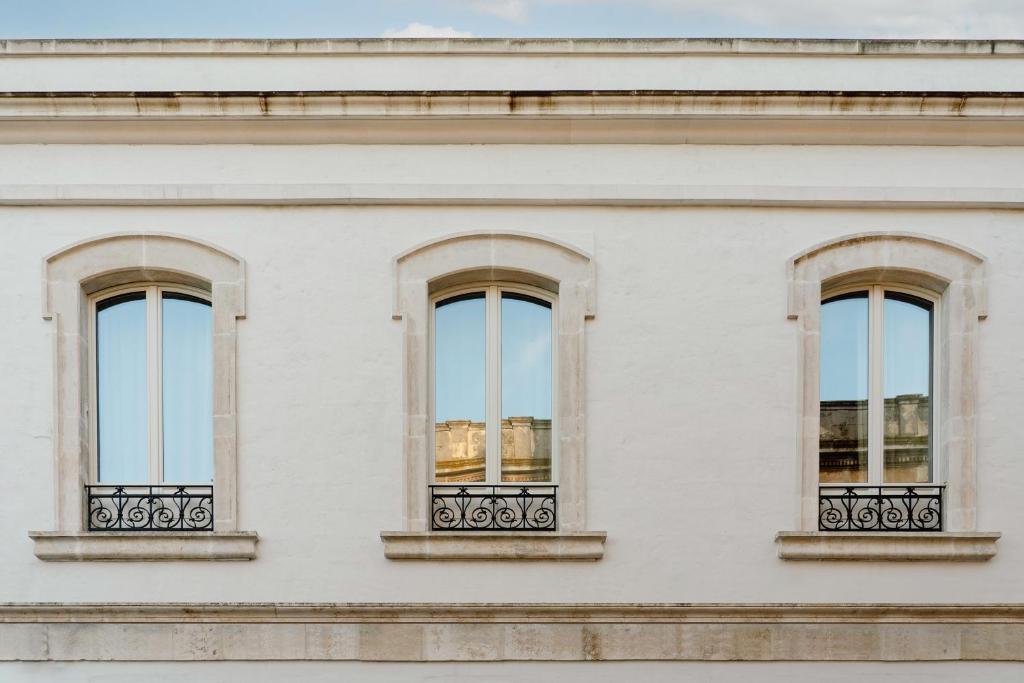a white building with three windows on it at Palazzo San Giuseppe in Ostuni