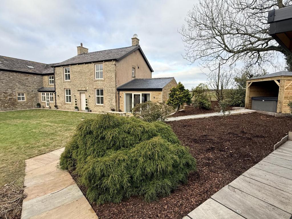 a large brick house with a landscaped yard at The Farm House in Skipton