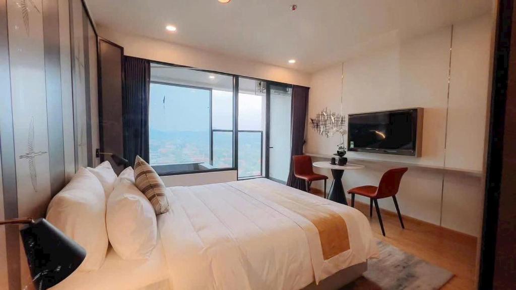 a bedroom with a large bed with a large window at Wyndham thanh thủy in La Phu