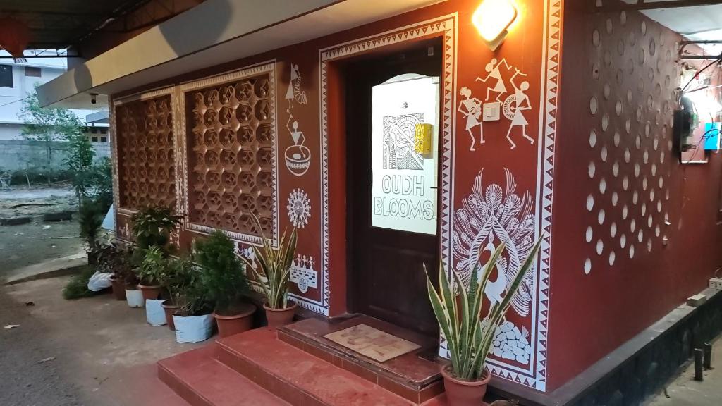 a building with potted plants in front of a door at Oudh blooms in Shoranūr