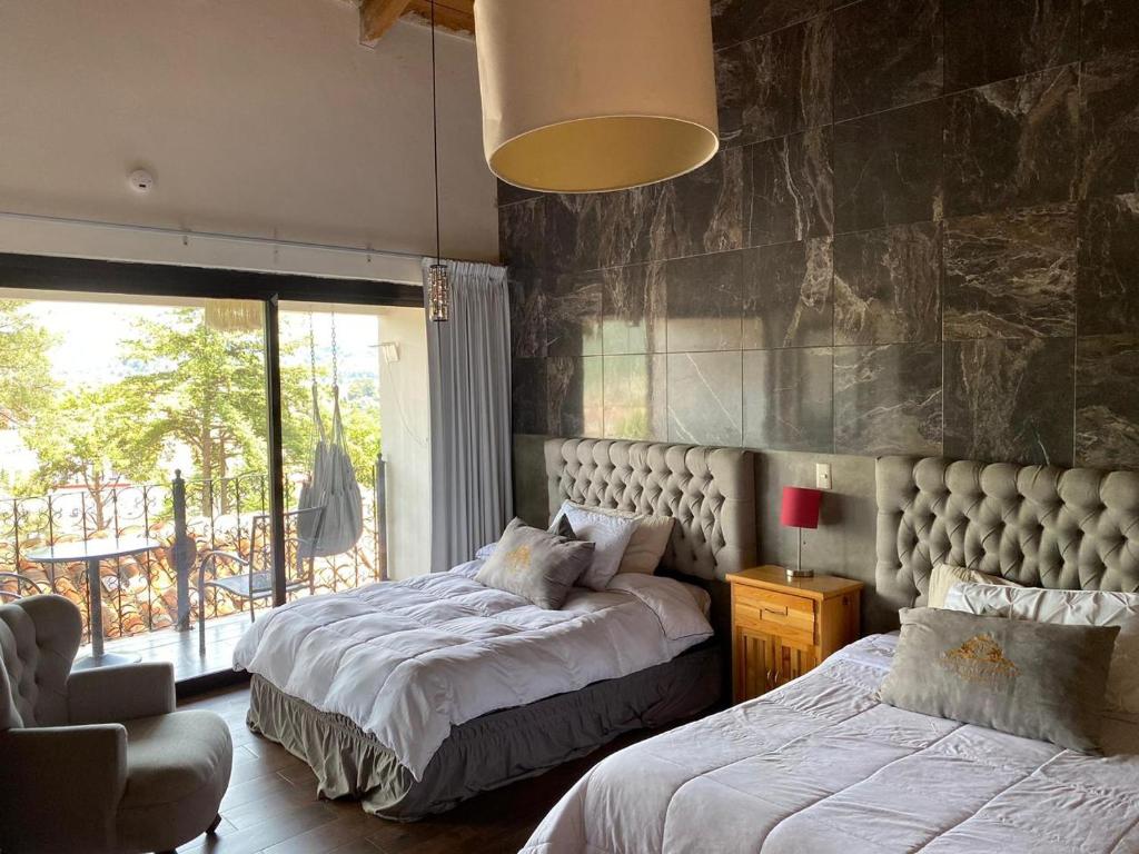 a bedroom with two beds and a large window at Departamentos San Francisco in San Cristóbal de Las Casas