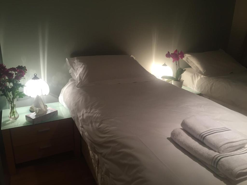 a bedroom with two beds and two lamps and flowers at Drummond Apartment in Edinburgh