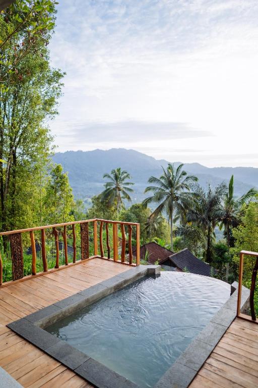 a plunge pool on a deck with a view of the mountains at Kubu Cemara Sidemen in Karangasem