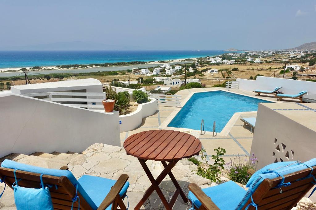 a patio with chairs and a swimming pool and the ocean at Villa Kamari in Kastraki