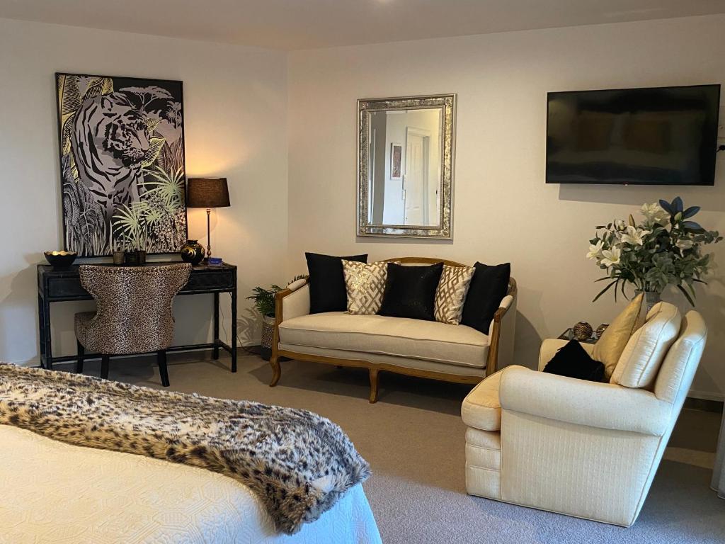 a room with a bed and a couch and a chair at Maison Blue - Chic Garden Apartment - Pet Friendly in Napier