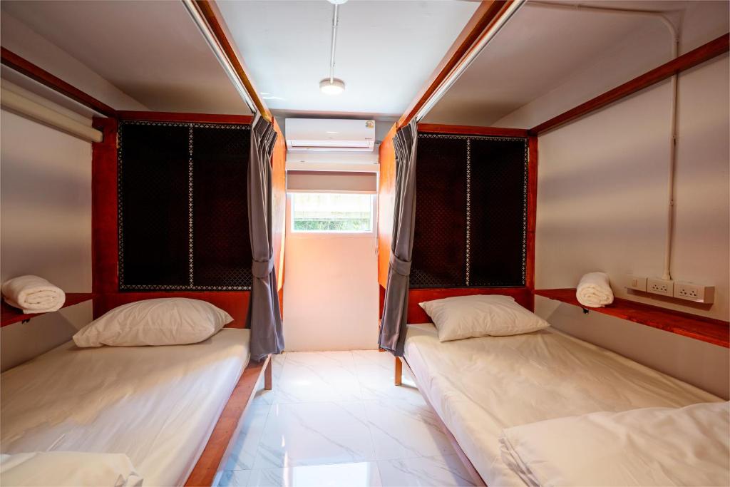 two beds in a room with red and black curtains at Coasta Wings Hostel in Nathon Bay