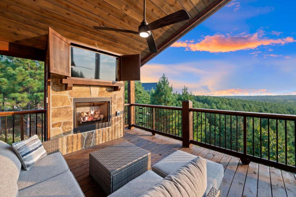 a living room with a fireplace on a deck at Spa Game Room Sunset Views 5BR Cabin in Broken Bow