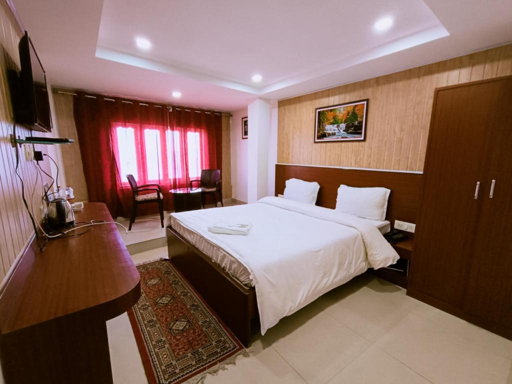 a hotel room with a large bed and a desk at Hotel Best Inn in Darjeeling