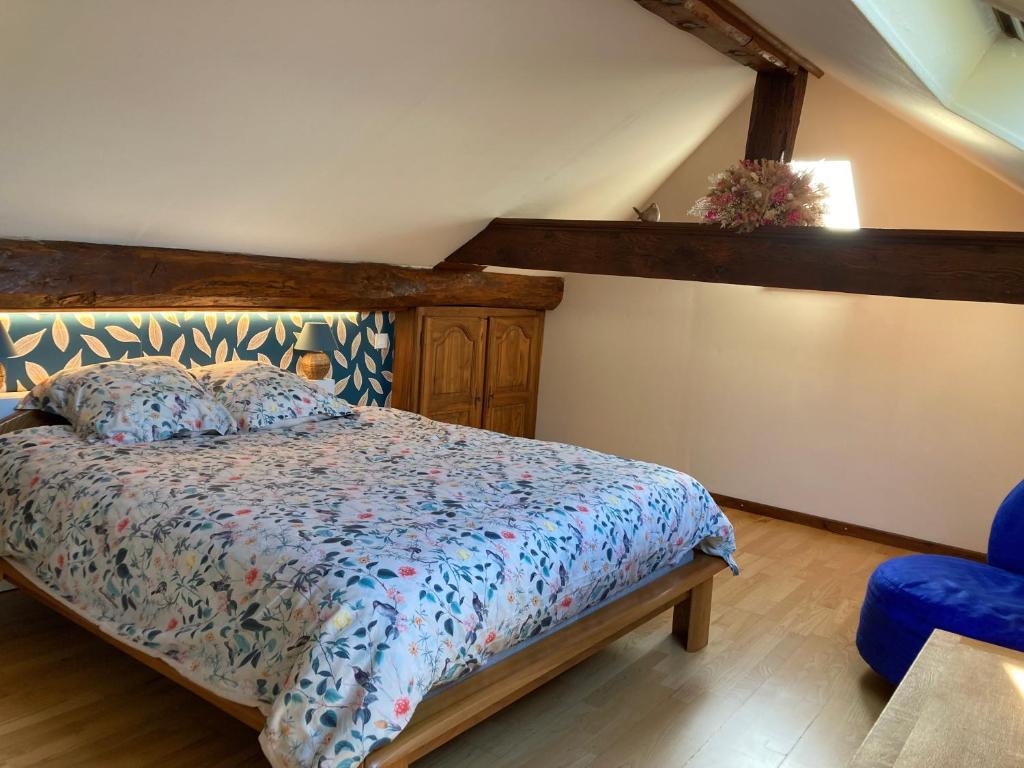 a bedroom with a bed with a blue comforter at Sous le bon Toit in Belley