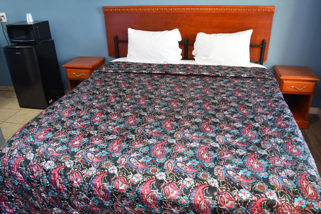 a bed with a colorful blanket on it with two tables at Corcoran Inn in Corcoran