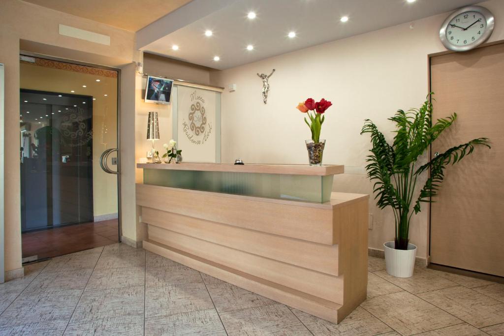 a lobby with a reception desk and a clock at Motta Residence Hotel in Motta SantʼAnastasia