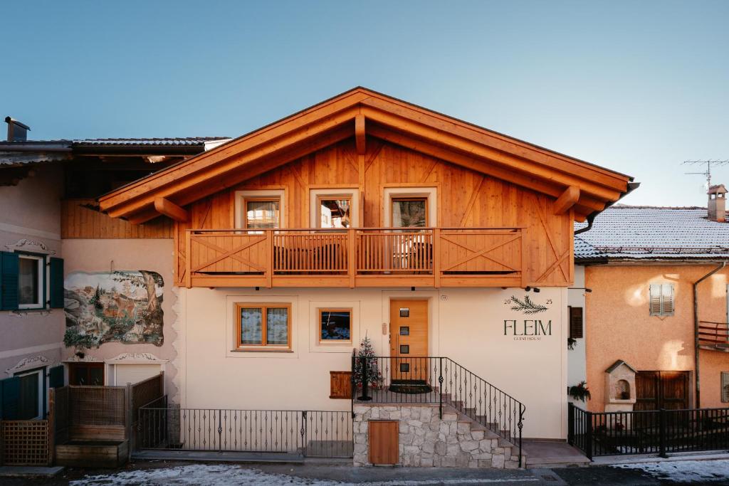 a wooden house with a balcony on top of it at Guest House Fleim in Panchià