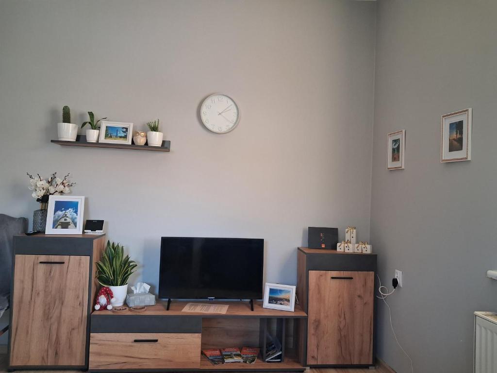 a living room with a tv and a clock on the wall at Sowie Pokoje in Jugów