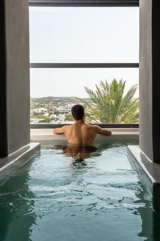 a man sitting in a swimming pool in a building at Uncle's House Junior Suite INDOOR Pool in Adamantas