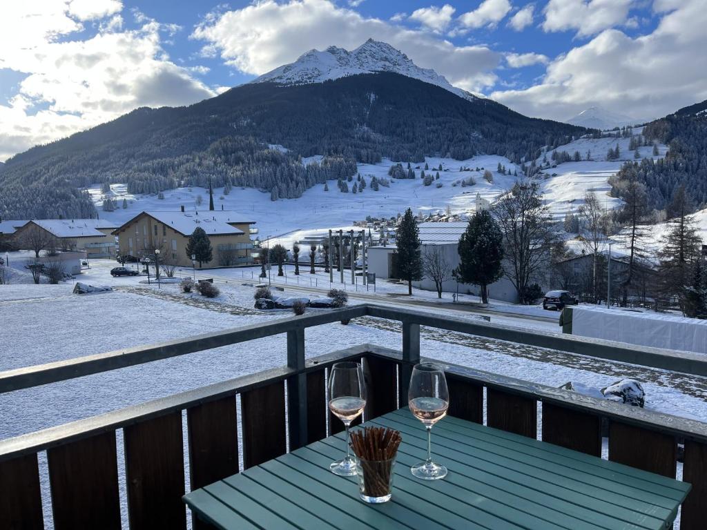 a table with wine glasses on a balcony with a mountain at Satin Home in Savognin